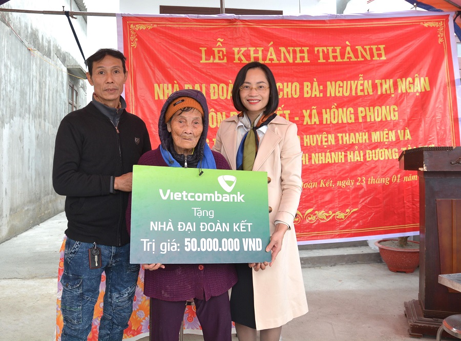 Bà Phạm Minh Đào - Phó Giám đốc Vietcombank Hải Dương (ngoài cùng bên phải) trao biển tặng nhà đại đoàn kết cho gia đình bà Nguyễn Thị Ngận, hộ nghèo thuộc huyện Thanh Miện, tỉnh Hải Dương.