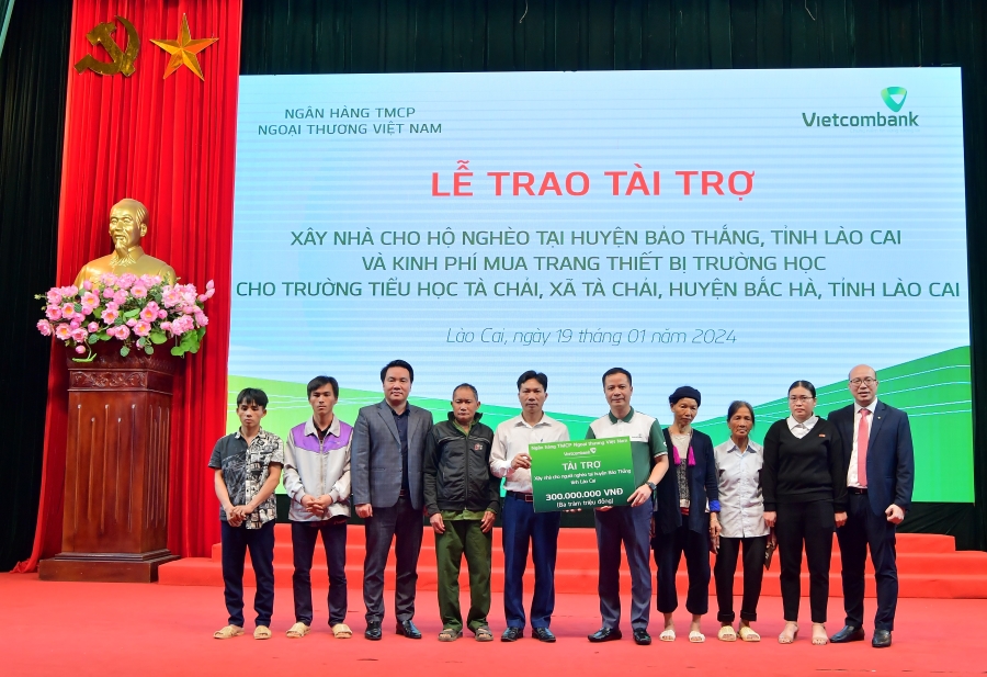 Ông Lê Hoàng Tùng - Phó Tổng Giám đốc Vietcombank (thứ 5 từ phải sang) cùng ông Đặng Việt Hùng - Giám đốc Vietcombank Lào Cai (ngoài cùng bên phải) trao biểu trưng hỗ trợ kinh phí xây dựng nhà cho 6 hộ gia đình khó khăn tại huyện Bảo Thắng, tỉnh Lào Cai.