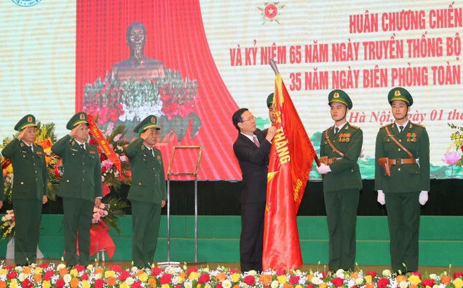 Chủ tịch nước Võ Văn Thưởng gắn Huân chương Chiến công hạng Nhì lên cờ truyền thống của Bộ đội Biên phòng. (Ảnh: Trọng Đức/TTXVN).